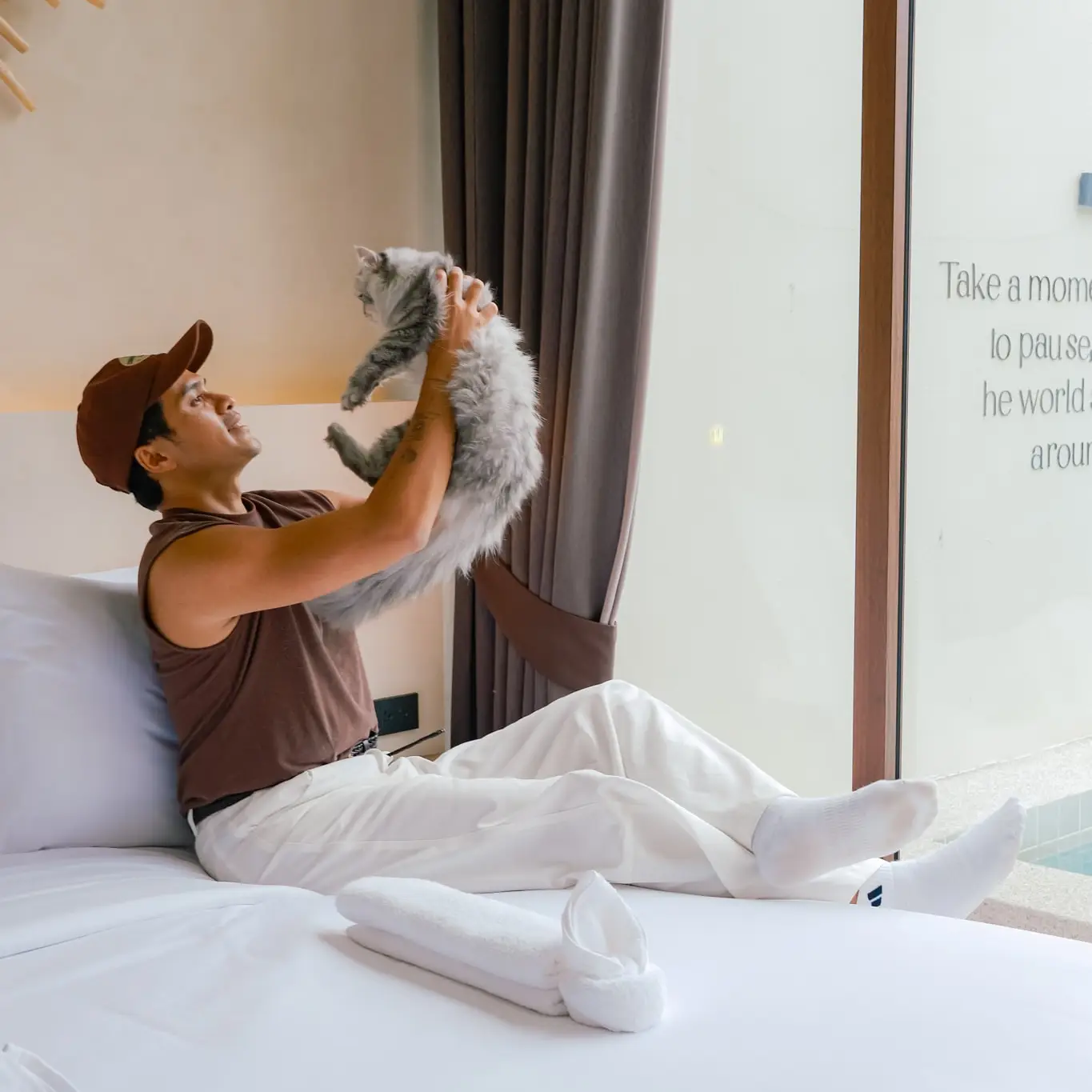 A guest lifting a small dog on the bed