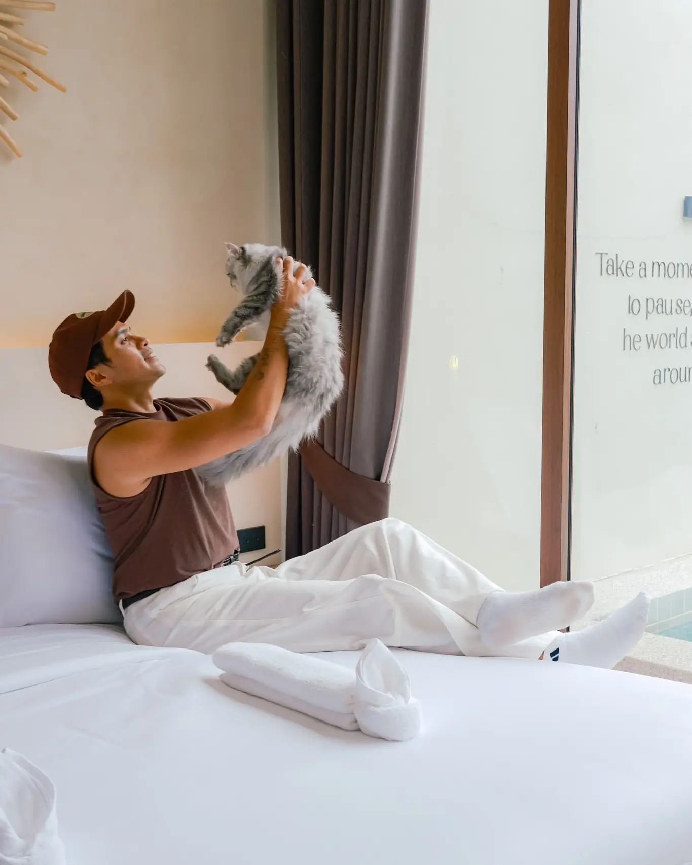A guest lifting a small dog on the bed
